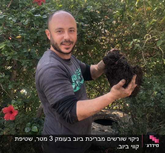 אדם מחזיק גוש אדמה ליד משאית ואקום